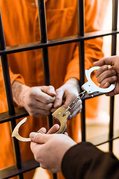 handcuffs-going-on-prisoner-in-orange-jumpsuit-through-jail-bars