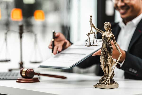 balance-of-laws-brass-statue-on-desk--with-man-holding-clipboard-in-background-for-expungement-and-sealing-records