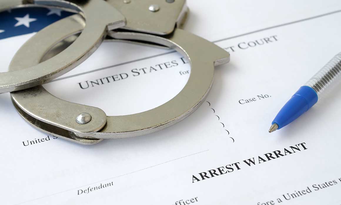 handcuffs-and-pen-laying-on-arrest-warrant-paperwork-for-the-united-states-of-america