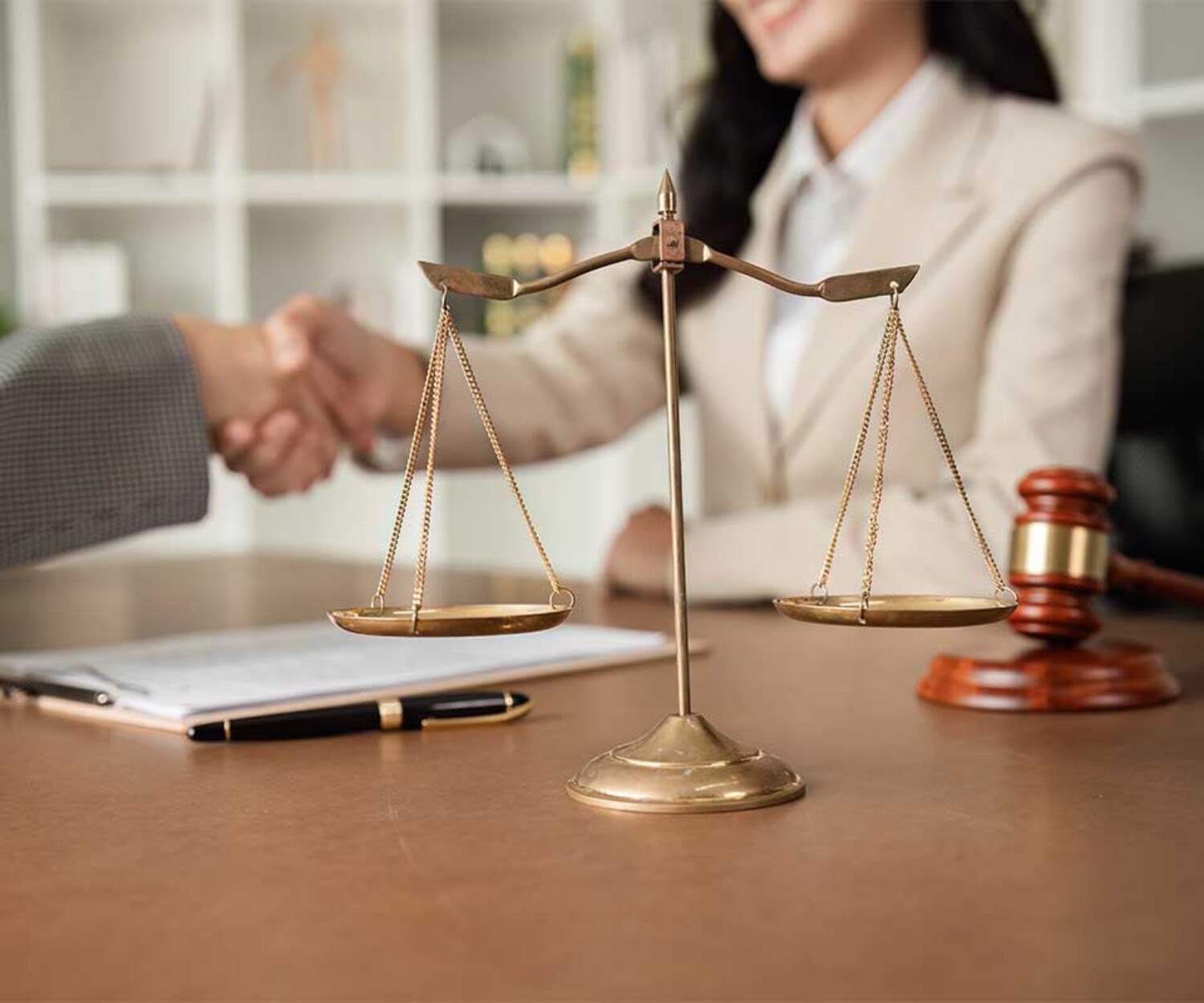 criminal-defense-attorney-shaking-hands-in-background-with-balance-of-the-law-statue-on-desk
