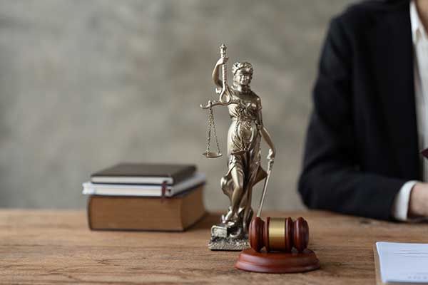 balance-of-laws-statue-on-desk-with-legal-books-in-background-and-arm-of-florida-federal-attorney-that-takes-firearm-cases