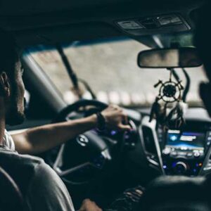 backseat-view-of-male-driving-a-car-with-dream-catcher-hanging-from-rearview-mirrow-signifying-traffic-attorney-defense-in-jacksonville